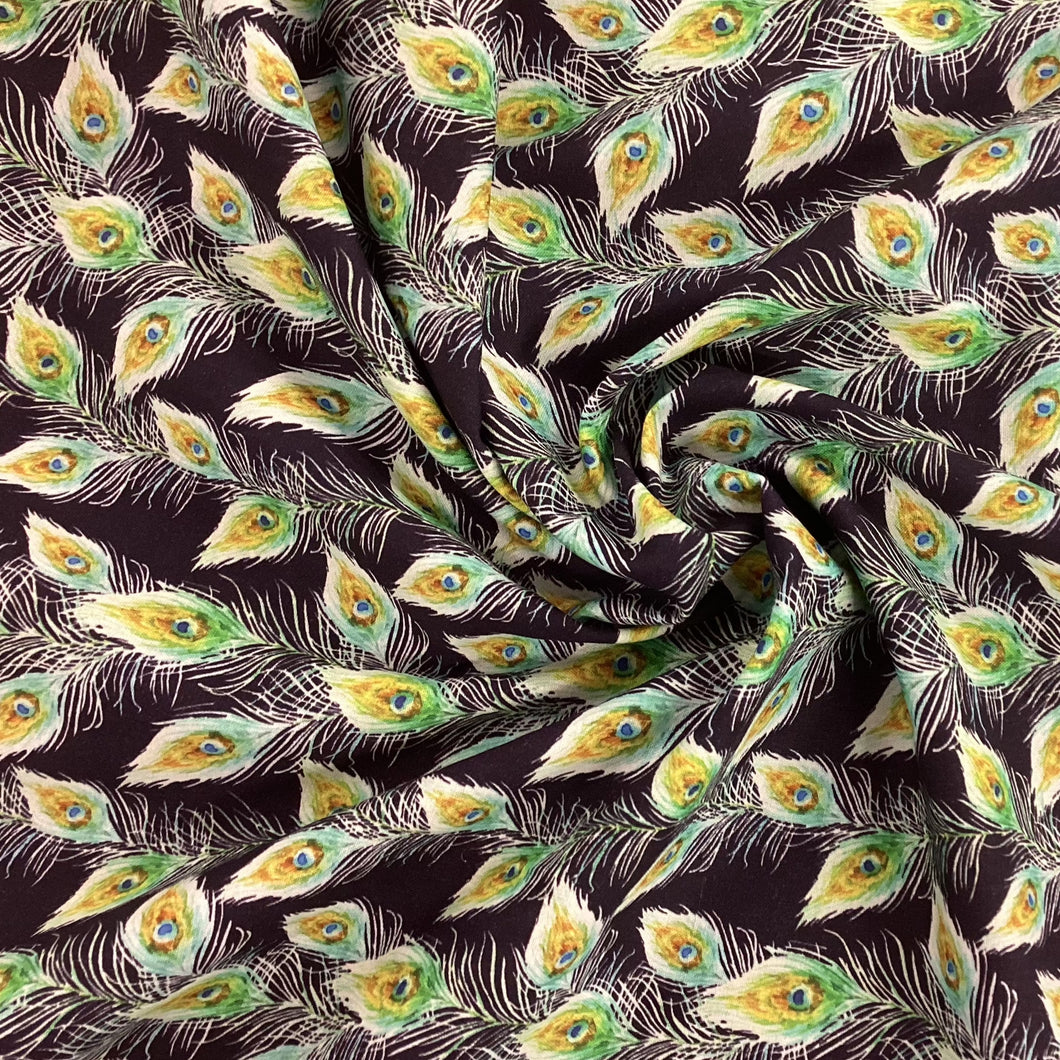 black fabric with peacock feathers green and yellow